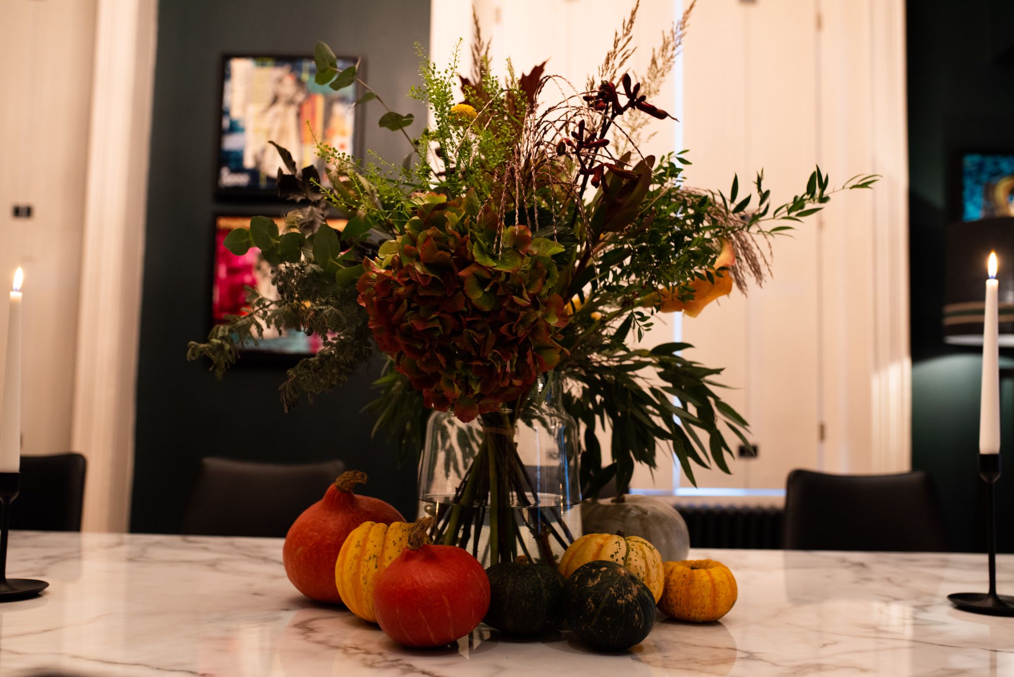 Flowers in a vase surrounded by pumpkins.