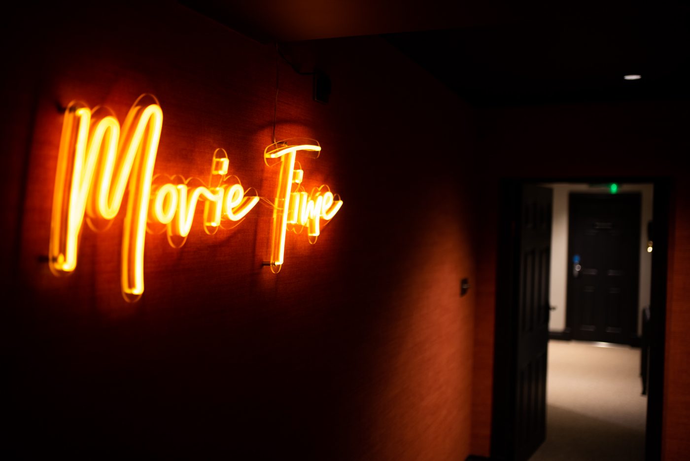 Neon sign saying "Movie time" on the wall of Edgar House cinema room
